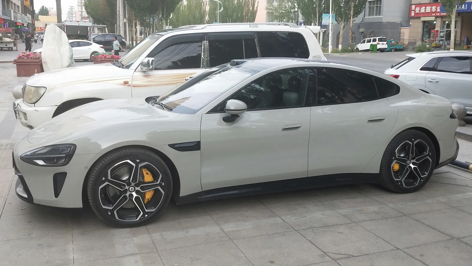 Xiaomi SU7 vue de trois quarts avant, carrosserie claire, sur fond urbain